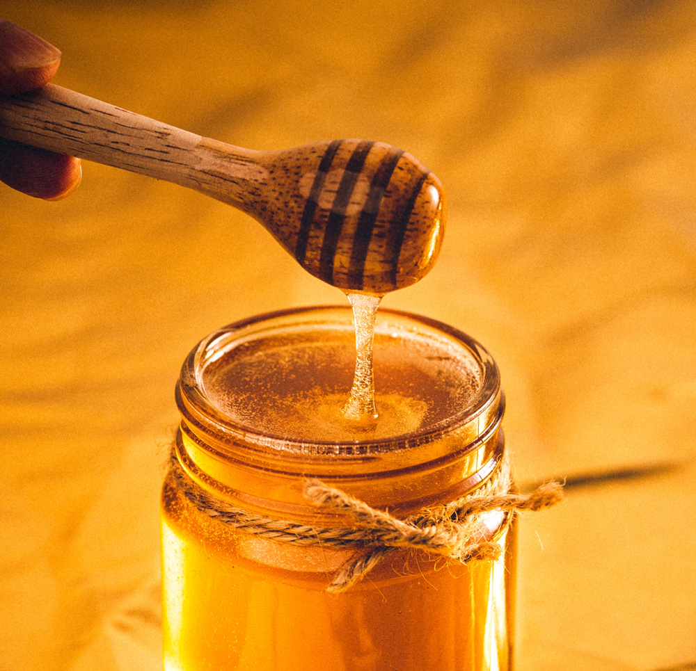 Wood honey spoon in a honey jar.